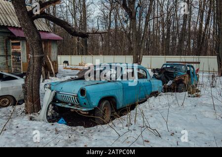 Vecchia auto retro sovietica arrugginita abbandonata coperta di neve. Foto Stock