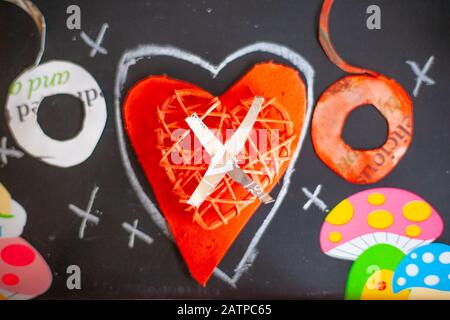 Ancora vita amore concetto per San Valentino - Mixed Media - Papercut lettere o X o argento-foderato X set su cuore dipinto e challked baci su ardesia. Foto Stock