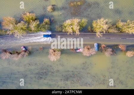 La foto datata gennaio 27th mostra un veicolo che ha guidato oltre le auto che sono state catturate sulla A1101 sul confine Cambridgeshire/Norfolk nelle recenti inondazioni e sono ora immediatamente visibili dopo che le acque alluvionali sono scese. Inondare l'acqua lungo un famigerato tratto di strada a Welney sul confine Cambridgeshire/Norfolk si è placato rivelando oggi un incredibile QUATTRO auto a trefoli (Mon). Gli automobilisti sono stati tutti presi dal lungo e tortuoso tratto di strada, che è stato allagato per due mesi. Quattro persone hanno dovuto essere salvate da una delle automobili da vigili del fuoco dopo che è stato catturato a Welney Wash su Janu Foto Stock