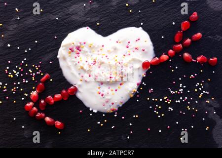 Ancora vita, amore e romanticismo lighthearted concetto - cocco yogurt cuore colpo di melograno freccia. Copyspace. Foto Stock