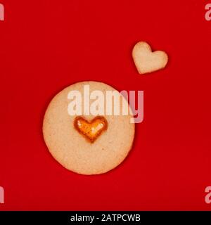 Dolci fatti a mano cute a forma di cuore su sfondo rosso. Concetto di San Valentino, sorprese con amore, vacanza, ecc piatto lay. Foto Stock