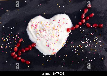 Ancora vita, amore e romanticismo lighthearted concetto - cocco yogurt cuore colpo di melograno freccia. Copyspace. Foto Stock