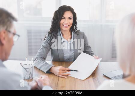 Indietro biew di coppia matura che firma il contratto a casa Foto Stock