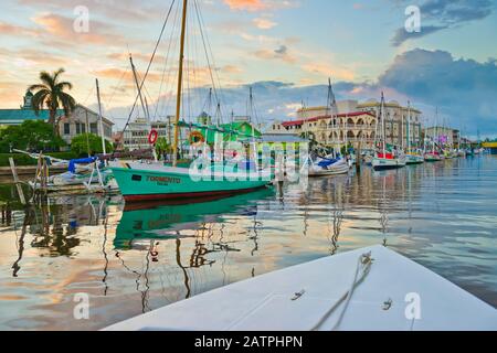 Colorato lungomare di Belize City al tramonto con riflessi in acque tranquille; Belize City, Belize District, Belize Foto Stock