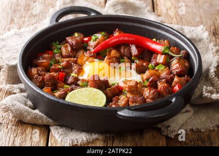 Saporito cibo filippino con uova, lime e peperoncino da vicino in una padella sul tavolo. Orizzontale Foto Stock