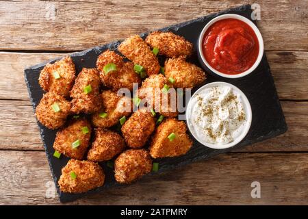 Delizioso pepite di pollo impanato con cocco servito con ketchup e maionese da vicino su una tavola di ardesia sul tavolo. Vista dall'alto orizzontale da abo Foto Stock