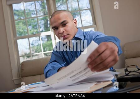 Giovane professionista maschile che lavora a un tavolo da casa Foto Stock