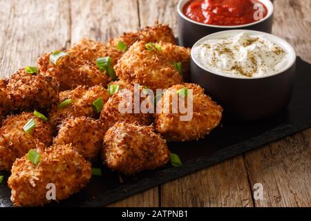 Delizioso pepite di pollo impanato con cocco servito con ketchup e maionese primo piano su una tavola di ardesia sul tavolo. Orizzontale Foto Stock