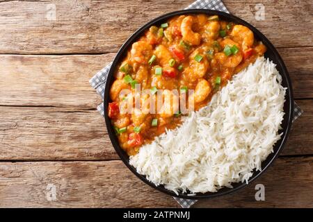 Servizio di gamberi Etouffee con verdure e salsa servita con il closeup di riso in un piatto sul tavolo. Vista dall'alto orizzontale Foto Stock