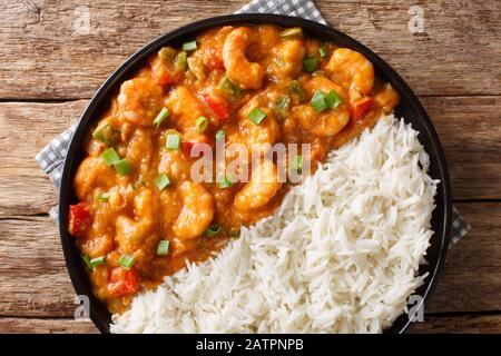 Gamberi tradizionali speziati Etouffee con sedano, cipolla e pepe con salsa servita con il closeup di riso in un piatto sul tavolo. Vista dall'alto orizzontale Foto Stock