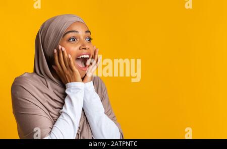 Ragazza nera in foulard guardando lo spazio della copia, esclamando con stupore Foto Stock