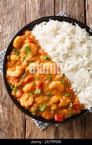 Gamberi Etouffee piatto Juicy soffocato in ricco e saporito roux salsa servita con il riso closeup in un piatto sul tavolo. Vista dall'alto verticale Foto Stock