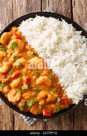 Gamberetto lo stufato classico della Louisiana Etouffee è composto da gamberetti, cipolla, sedano e pepe verde servito con il riso in un piatto sul tavolo. Verticale Foto Stock