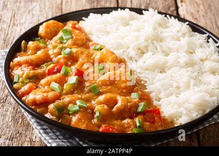 Gamberi Creole Etouffee piatto con sedano, cipolla e pepe cotto in salsa roux servito con riso primo piano in un piatto sul tavolo. Orizzontale Foto Stock