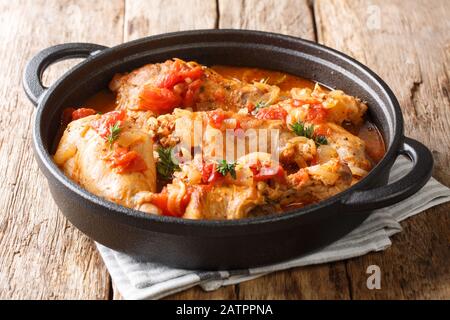 Gustoso stufato di coniglio piccante in salsa di pomodoro con vino bianco ed erbe da vicino in una padella sul tavolo. Orizzontale Foto Stock