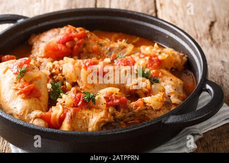 Cunillo stufato di coniglio in salsa di pomodoro con vino bianco ed erbe da vicino in una padella sul tavolo. Orizzontale Foto Stock