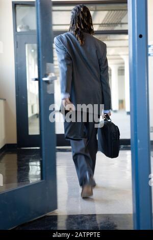 Un giovane che cammina attraverso una porta. Foto Stock