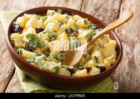Insalata di patate marocchina tradizionale con erbe, spezie e olive essiccate condite con yogurt da vicino in una ciotola sul tavolo. Orizzontale Foto Stock