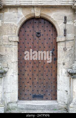 Porta chiodati in legno con campana in ottone, Cotswolds England Foto Stock
