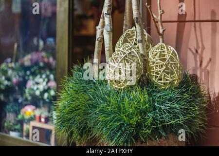 Uova di Pasqua su decorazioni in erba sulla strada di fronte al negozio di fiori Foto Stock