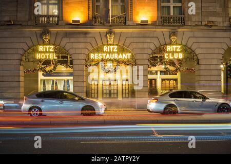 Il Ritz Hotel and Restaurant si è illuminato di notte con decorazioni natalizie appese. Lunga esposizione con le luci delle auto che passano davanti. Londra Foto Stock