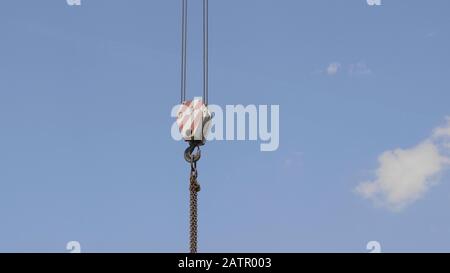 Il gancio della gru con strisce rosse e bianche pensili, cielo blu in background. Foto Stock