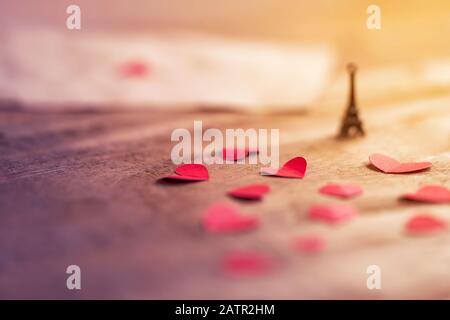 Graziosa e romantica Torre Eiffel in miniatura con piccoli cuori rossi su una superficie in legno con spazio per il testo. Sfondo per il giorno della San Valentino, matrimonio, regalo, gr Foto Stock