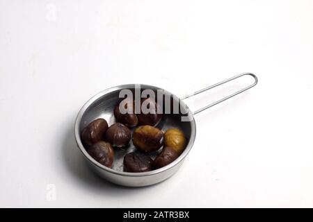 padella di castagne fritte isolate su fondo bianco piatto. L'immagine contiene spazio di copia Foto Stock