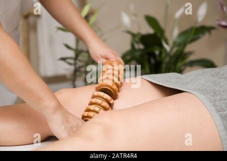 Closeup del massaggio anti-cellulite della maderoterapia con massaggiatore a rulli in legno Foto Stock