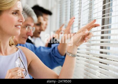 Vista dei dirigenti aziendali sbirciando attraverso le persiane. Foto Stock