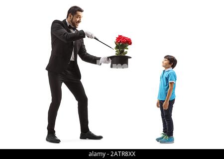 Scatto a tutta lunghezza di un mago che fa un trucco del cappello con i fiori davanti ad un ragazzo isolato su sfondo bianco Foto Stock