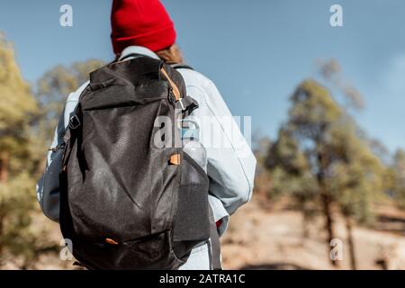 Giovane donna vestita casualmente camminando con zaino nella foresta molto in montagna sulle rocce vulcaniche Foto Stock