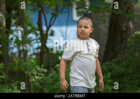 Ragazzo pre-teen fuori con gli alberi sullo sfondo Foto Stock