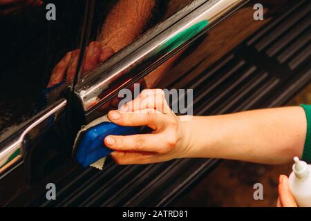 Un impiegato del lavaggio dell'automobile lava completamente conduce la deviazione ed applica l'apparecchiatura protettiva al corpo di un automobile costosa Foto Stock