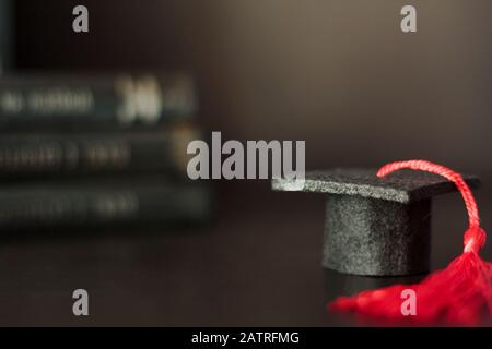 Cappellino di graduazione con mucchio di libri sullo sfondo. Con spazio di copia. Concetto di istruzione e laurea Foto Stock