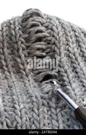 Tessitura a maglia grigio chiaro con difetto di fabbricazione isolato su bianco. Risoluzione dei problemi Foto Stock