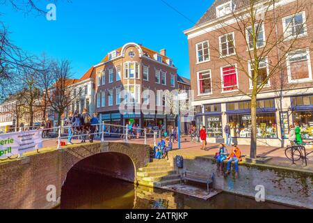 Delft, Paesi Bassi - 8 aprile 2016: Colorata vista sulla strada con case tradizionali olandesi, ponte, gente e canale Foto Stock