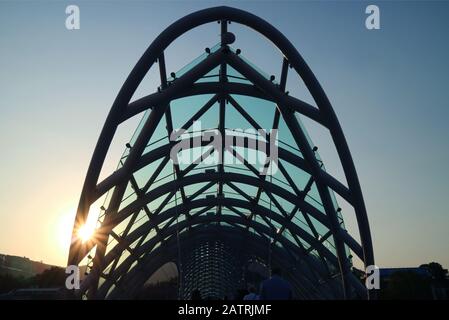 Splendente sole che splende attraverso il Ponte della Pace, splendido punto di riferimento di Tbilisi, Georgia Foto Stock