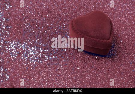 anello a forma di cuore di velluto rosso con glitter su sfondo rosso. Regalo per San Valentino o compleanno. Copiare lo spazio per il testo Foto Stock