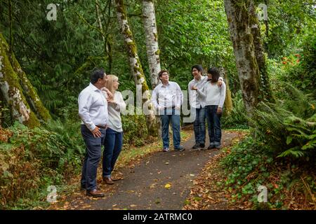 La famiglia cammina e parla su un sentiero in un parco con foresta; Langley, British Columbia, Canada Foto Stock