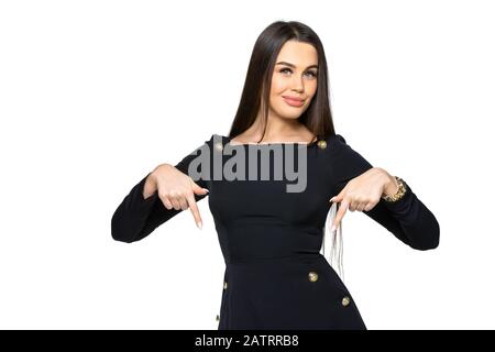 donna punta le dita verso il basso. ragazza in abiti scuri su uno sfondo bianco isolato. donna brunetta Foto Stock