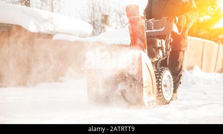 Uomo pulizia neve da marciapiedi con motoslitta inverno Foto Stock