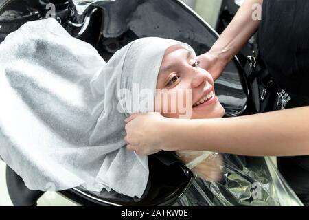 Parrucchiere professionale che asciuga i capelli della donna dopo il lavaggio con un asciugamano Foto Stock