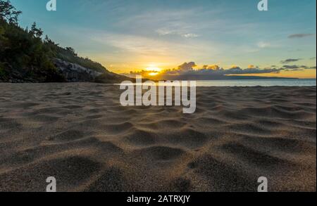 Il sole tramonta all'orizzonte su questa foto panoramica della superficie nella soffice sabbia bianca di una spiaggia; Maui, Hawaii, Stati Uniti d'America Foto Stock