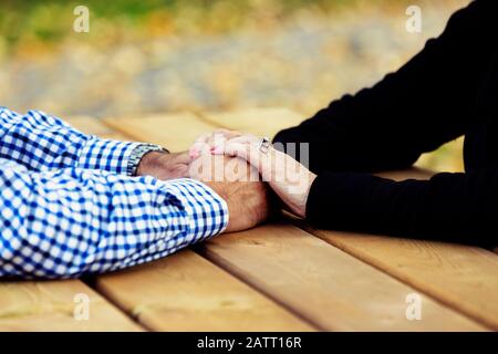 Una coppia matura che prega insieme ad un tavolo da picnic dopo aver trascorso un po' di tempo di qualità a discutere la loro fede; St. Albert, Alberta, Canada Foto Stock