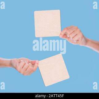 Mani che tengono un legno bianco su sfondo blu Foto Stock