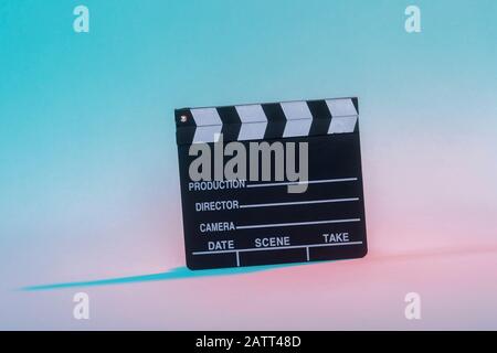 Film clapper su sfondo neon, concetto di cinema. Foto Stock