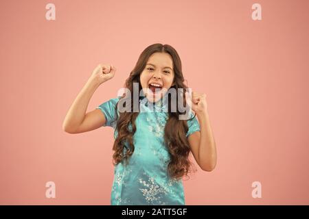 Shes un vero vincitore. Bambina gridare e fare vincitore gesto su sfondo rosa. Felice piccolo vincitore active gesticolando in stile cinese. Emozionato il vincitore celebrare la vittoria o il successo. Foto Stock