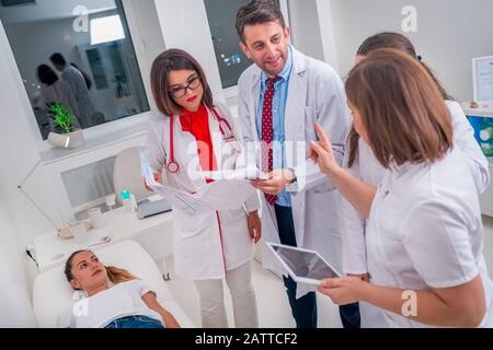 Il gruppo di medici in piedi accanto a un malato e discutere le cause per la sua malattia. Foto Stock