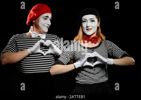 I mimes fanno le forme del cuore con le mani. Uomo e donna come mimo artisti Foto Stock